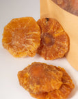Dehydrated pineapple slices for drink garnishes, displayed beside a kraft paper pouch