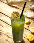 Iced matcha latte with dehydrated lemon garnish and straw on wooden table in sunlight