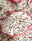 Close-up of dehydrated dragon fruit slices with white flesh and black seeds, pink rind visible.