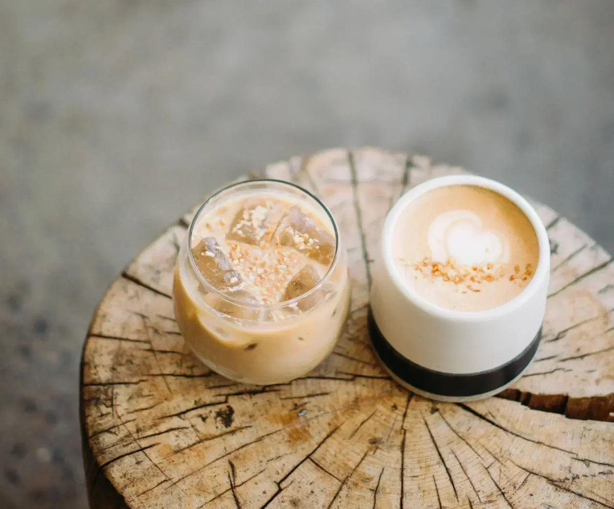 Iced coconut latte and hot latte with coconut flakes on rustic wooden table