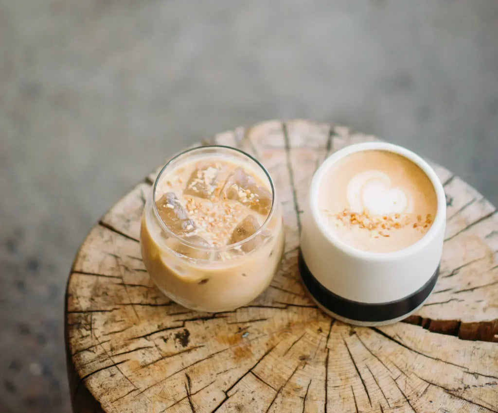 Iced coconut latte and hot latte with coconut flakes on rustic wooden table
