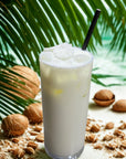 Iced coconut latte with a straw, surrounded by coconuts and palm leaves, tropical setting