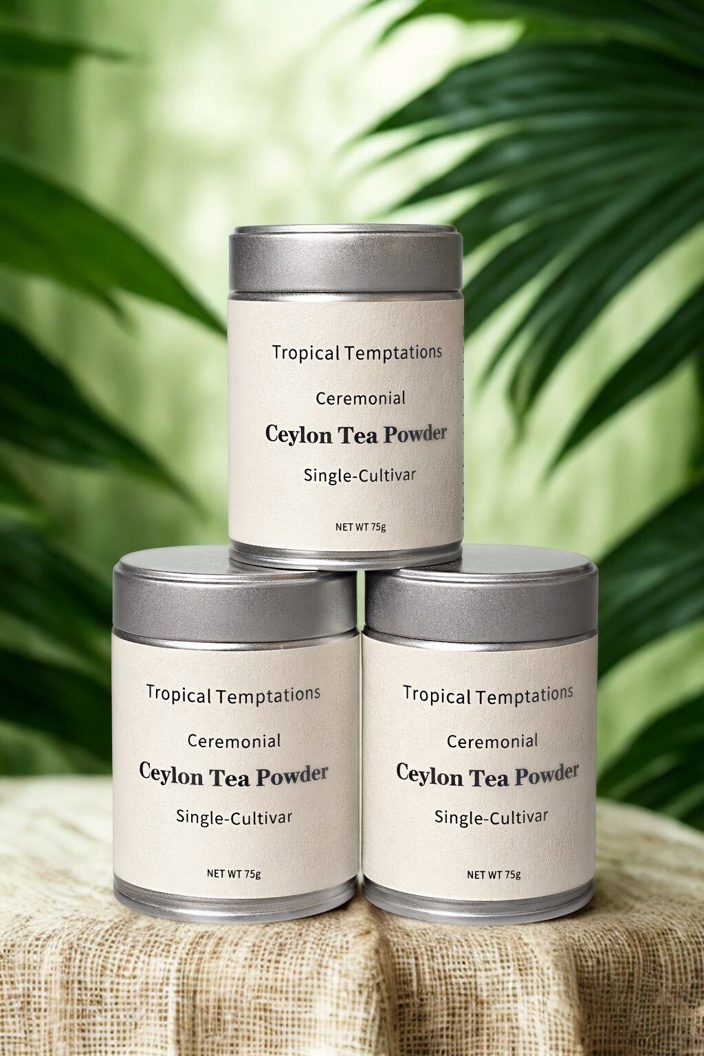 Three ceremonial Ceylon tea powder tins stacked on fabric with tropical leaves in background