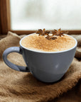 Creamy latte with cinnamon and star anise garnish in a mug on burlap fabric