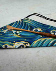 Bamboo matcha scoop on blue wave-patterned fabric pouch for tea rituals