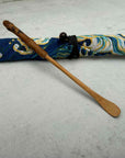Bamboo matcha scoop with decorative blue patterned cloth pouch on light surface