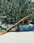 Wooden matcha whisk spoon on colorful patterned cloth with succulent plants in background